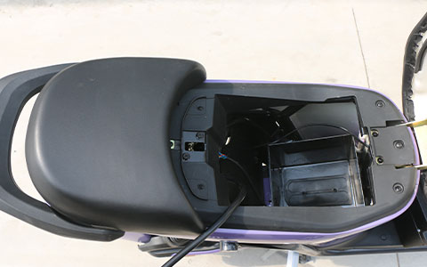 Purple Electric Scooter | Removable Battery Compartment Detail Open battery compartment under the seat of purple electric bicycle, showing the removable battery installation space