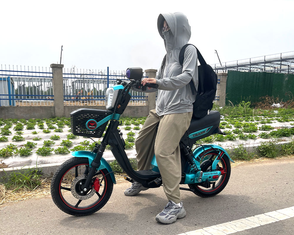 Electric Bike | Front Riding Outdoor Shot Front view adult rider on teal electric bicycle with super bright front headlamp