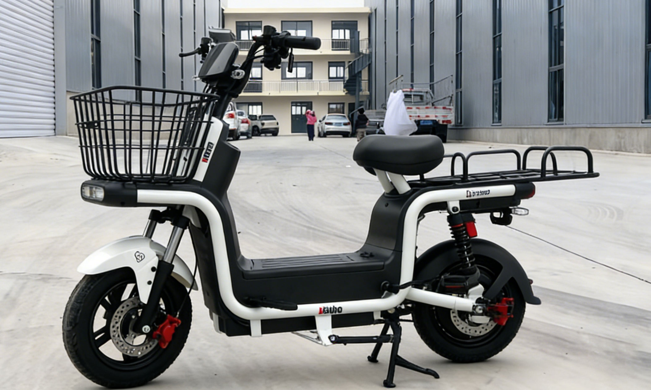 Modern white and black electric bike with front basket, dual disc brakes, rear shock absorption, and rear cargo rack for urban commuting