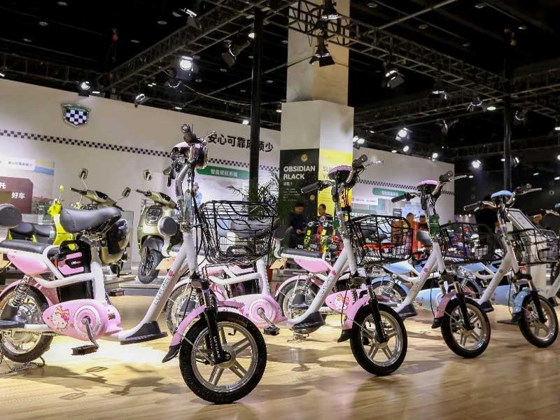 Exhibition display of colorful electric bicycles, including pink and blue models, at a new energy ve