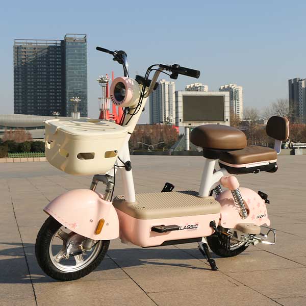 A pink and beige electric bicycle, located in the square with urban facilities such as tall buildings and large screens in the background.